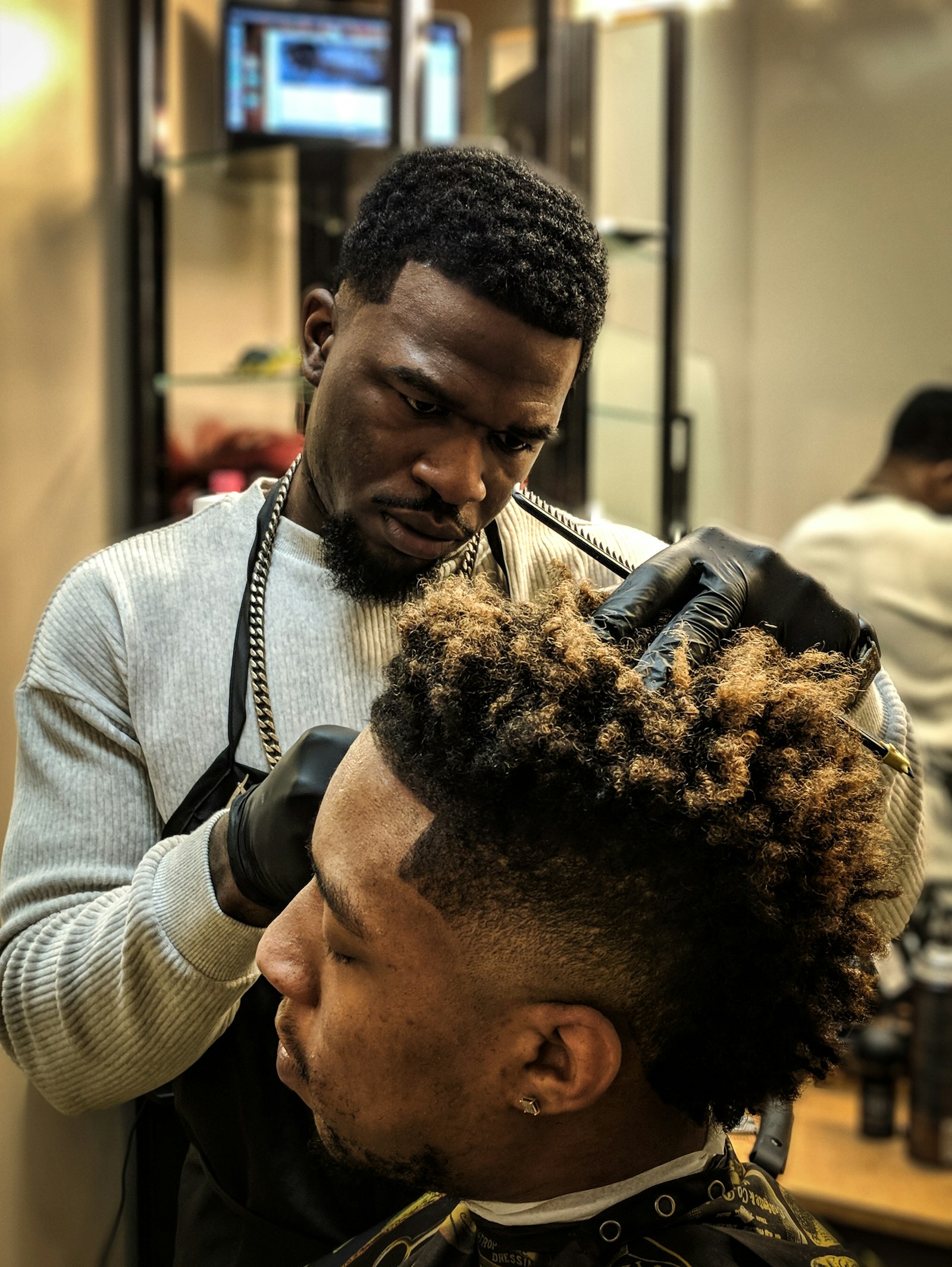 Barber Dez Whitfield shaping a client's curly fade with clippers