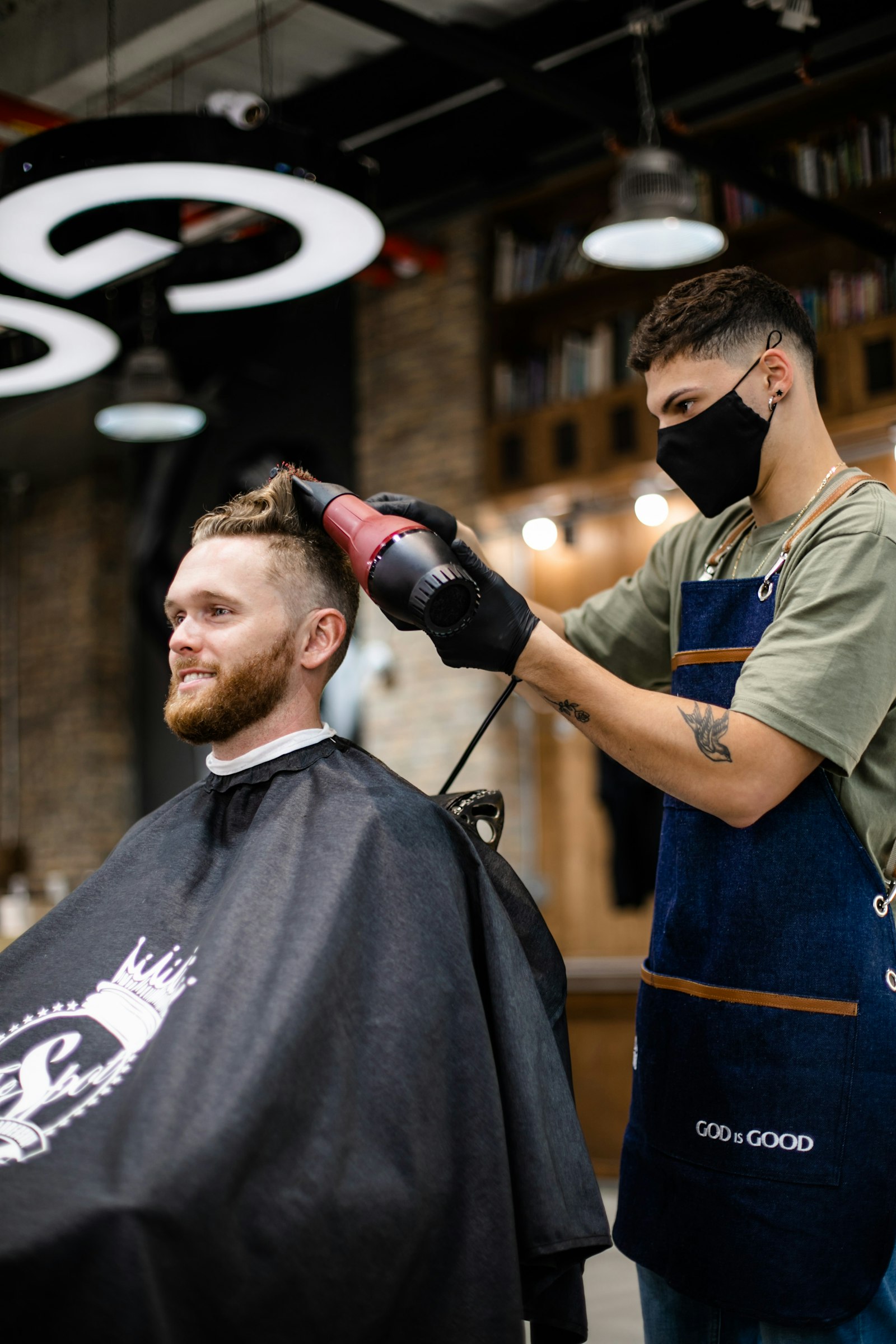Barber blow-drying and finishing a client's cut in the chair