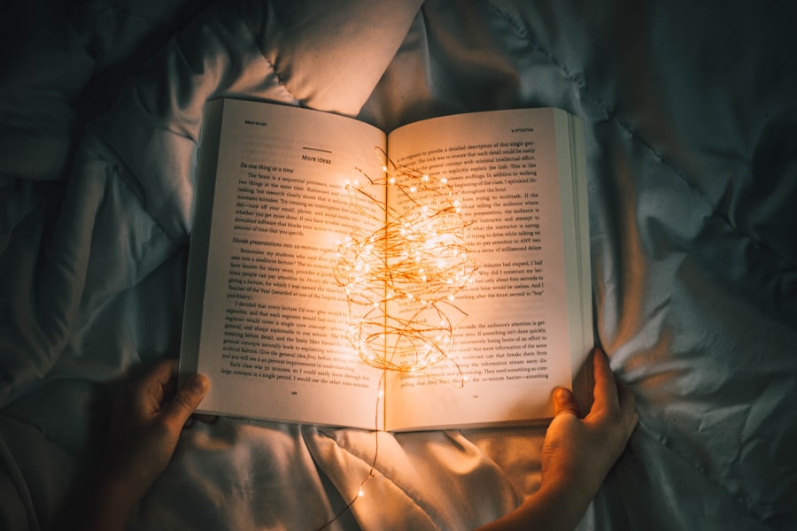 An open book held in two hands, lit from within by a tangle of warm fairy lights.