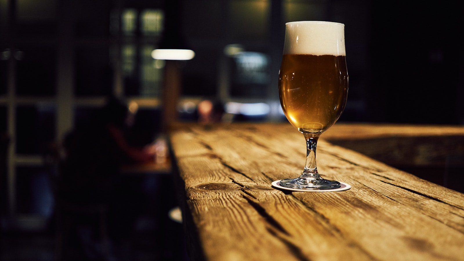 A glass of golden Wildpine ale resting on the reclaimed-timber bar in the quiet taproom.