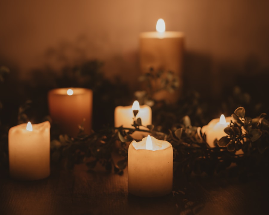 A cluster of ivory pillar candles burning together among dark foliage, bathing the scene in warm amber light.
