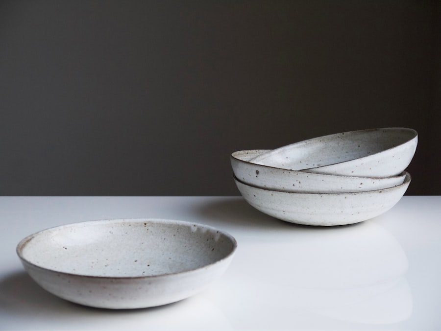 Three shallow speckled stoneware pasta bowls, one in front and two stacked behind.