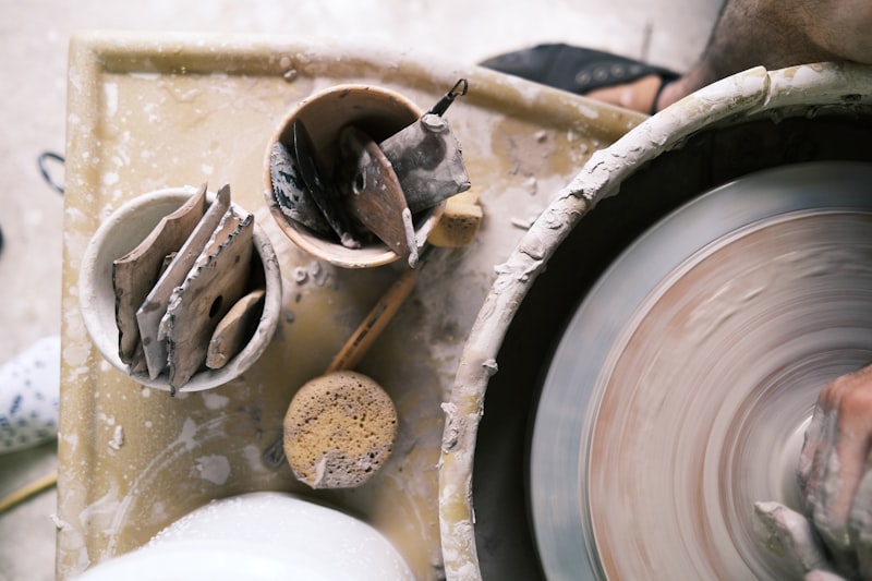 Overhead view of a potter's wheel spinning beside a tray of ribs, sponges and trimming tools.