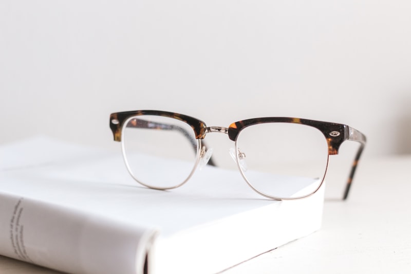 Lunet Hale browline frames with a tortoiseshell brow and silver wire rims, resting on a white book