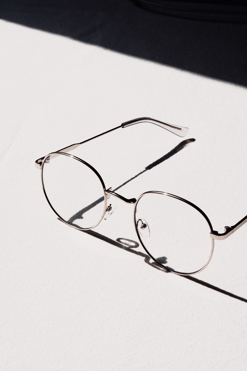 Lunet Atlas round wire frames in gold, casting a hard shadow on white linen