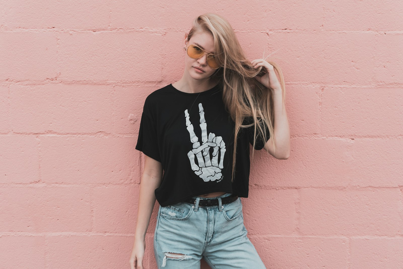 Model in a cropped black graphic t-shirt with a white hand print, worn with light jeans