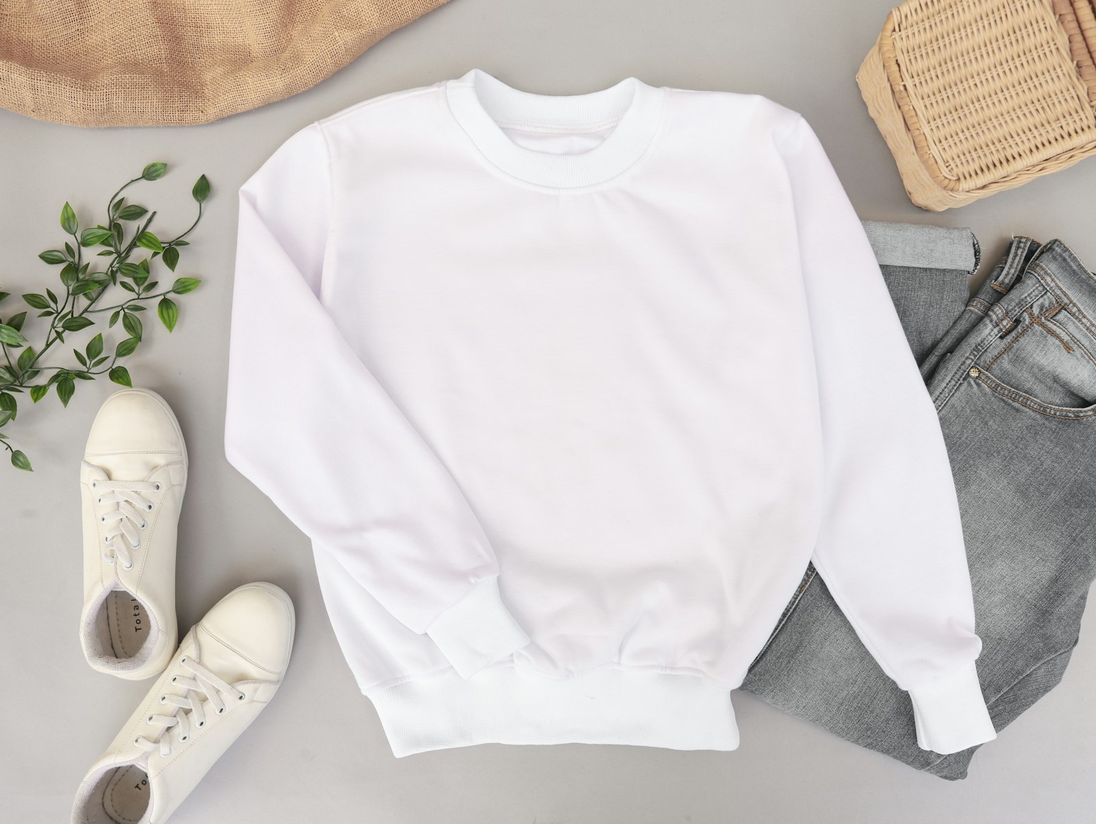 Plain white crewneck sweatshirt laid flat on a grey surface