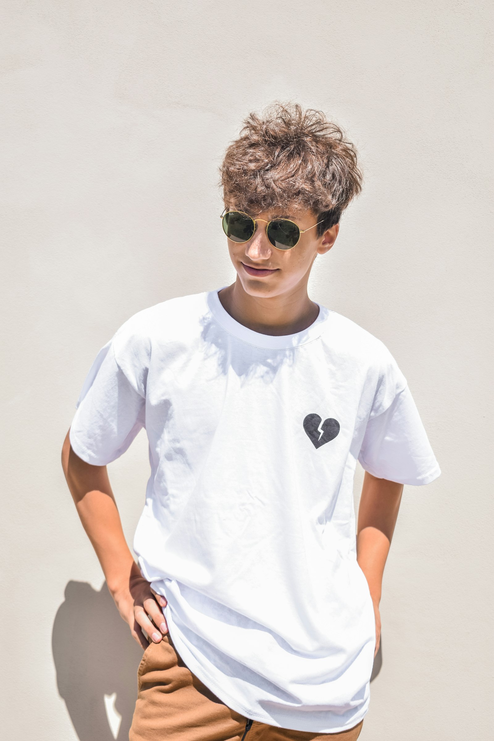 Model in a plain white heavyweight tee with a small chest mark, shot in daylight