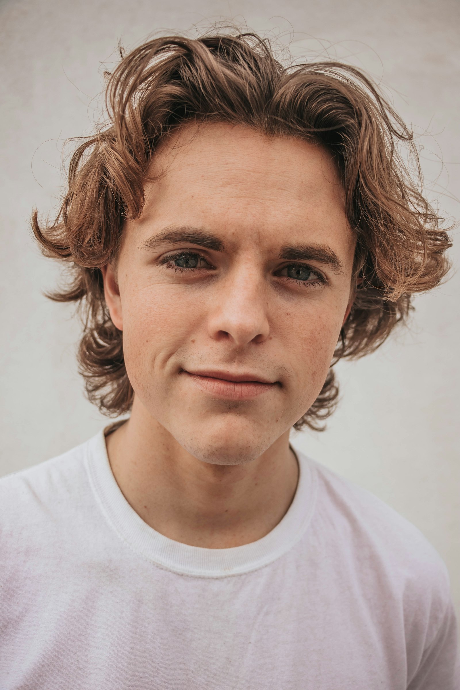 Portrait of a model in a plain white heavyweight tee against a pale studio wall
