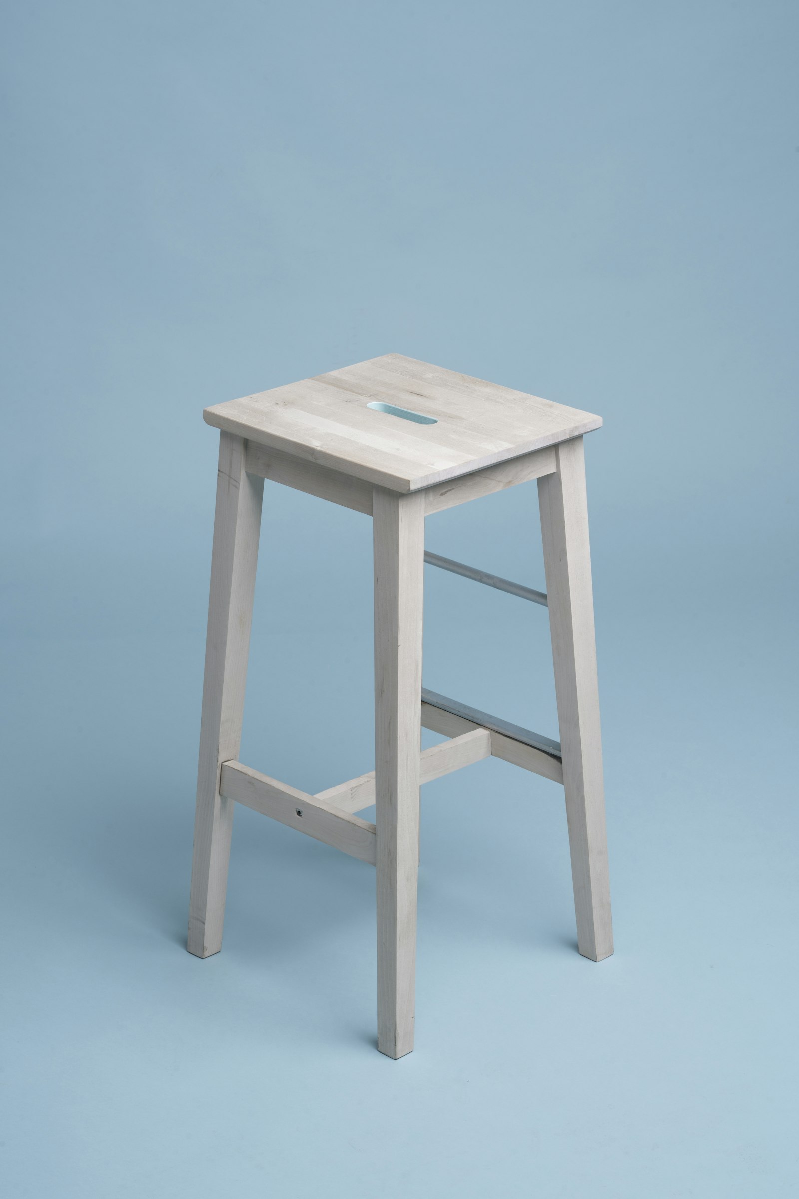 Whitewashed solid-wood bar stool with a handle slot cut into the seat