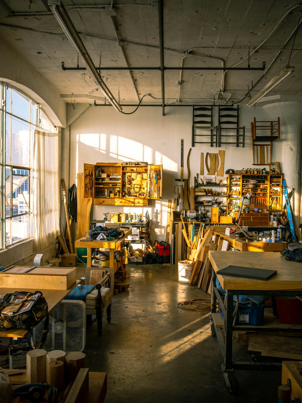 The Norra Living workshop in evening light: timber stock, hand tools on the wall and chair frames in progress