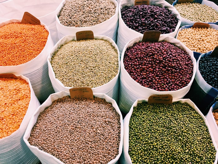 Open sacks of red lentils, split peas, mung beans and pulses with handwritten paper tags