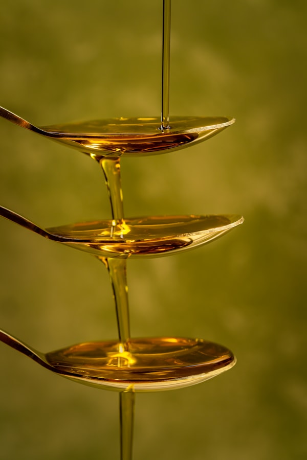 Golden oil pouring in a thread across three stacked spoons