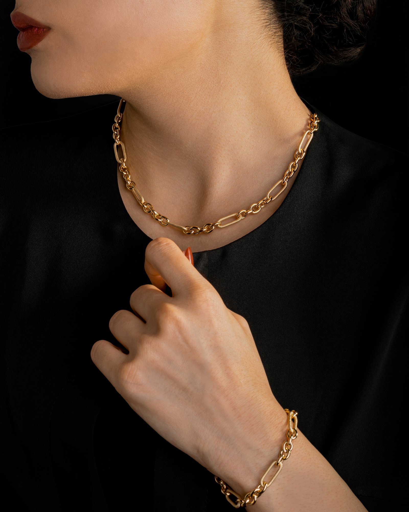 Model wearing the Cordelle 18k gold link chain and matching bracelet against black