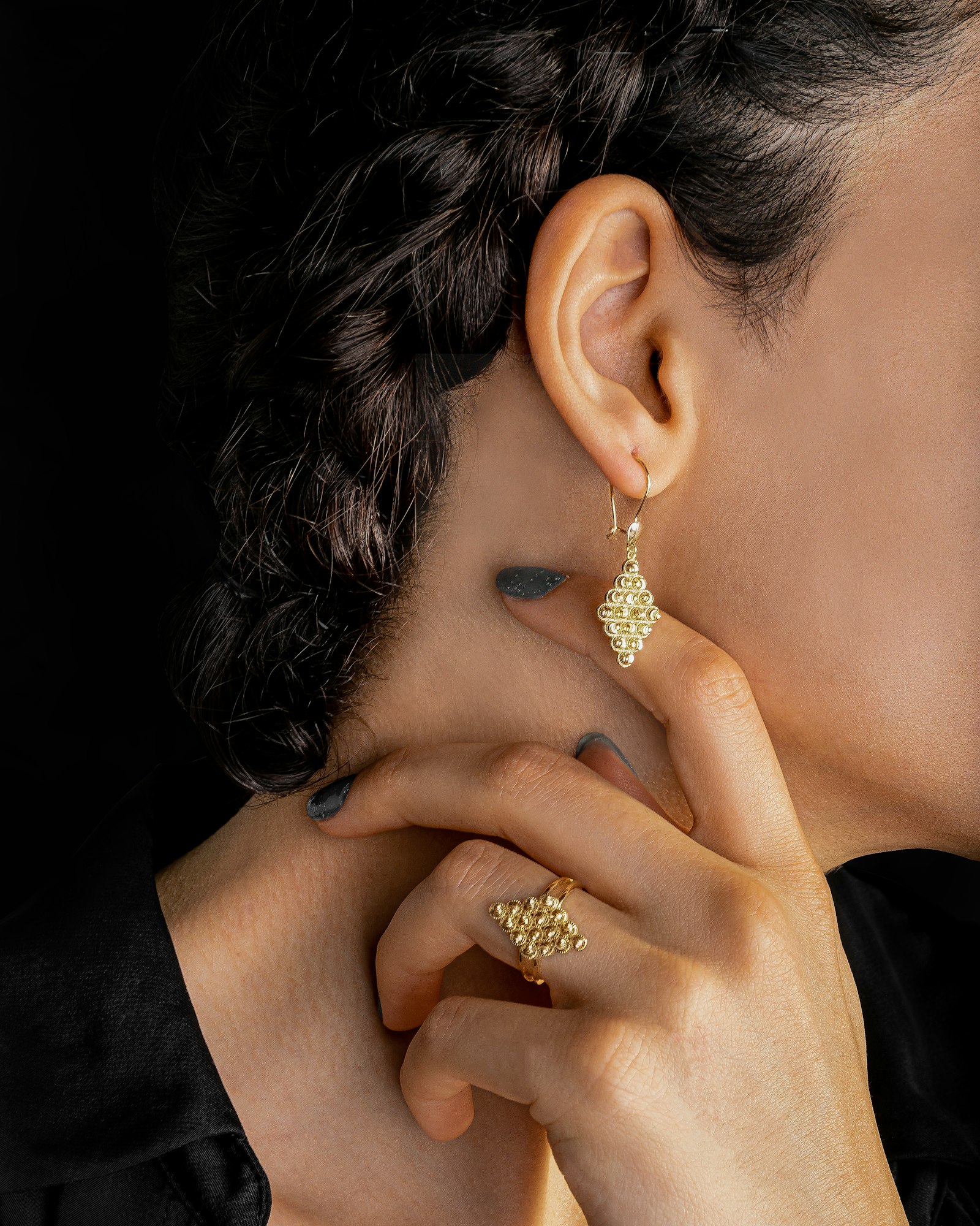 Model wearing the Granule granulated gold drop earring and stacked ring