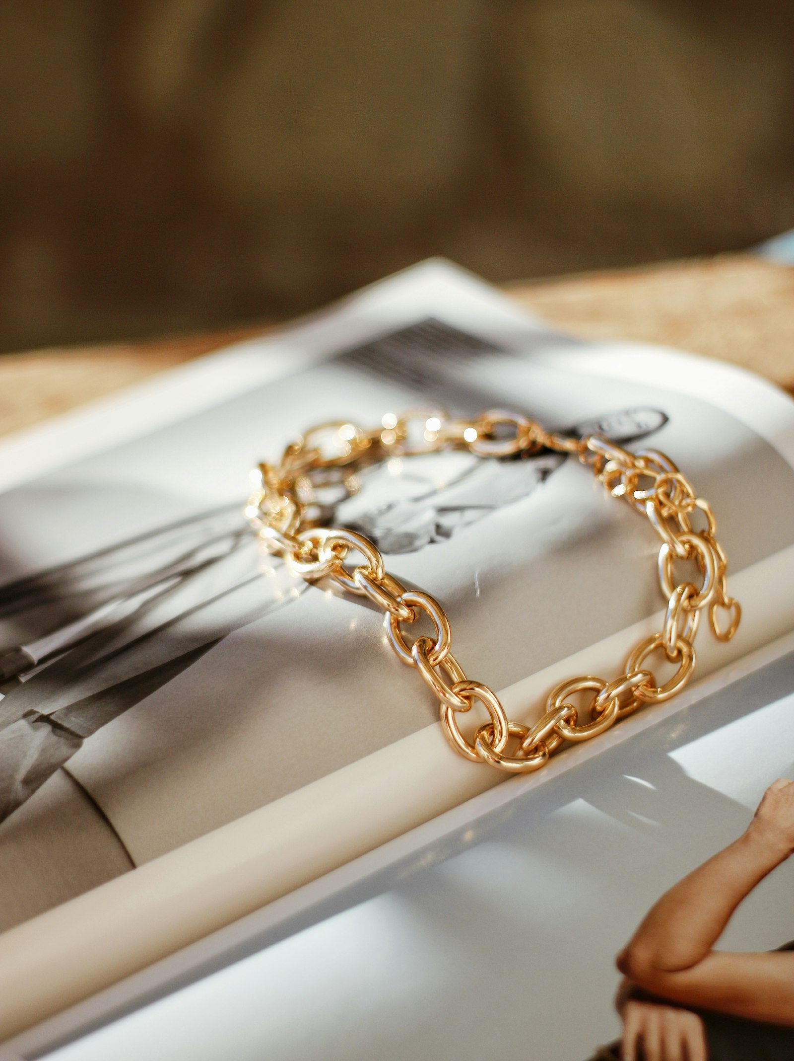 The Cordelle heavy oval-link bracelet in 18k gold laid across an open magazine