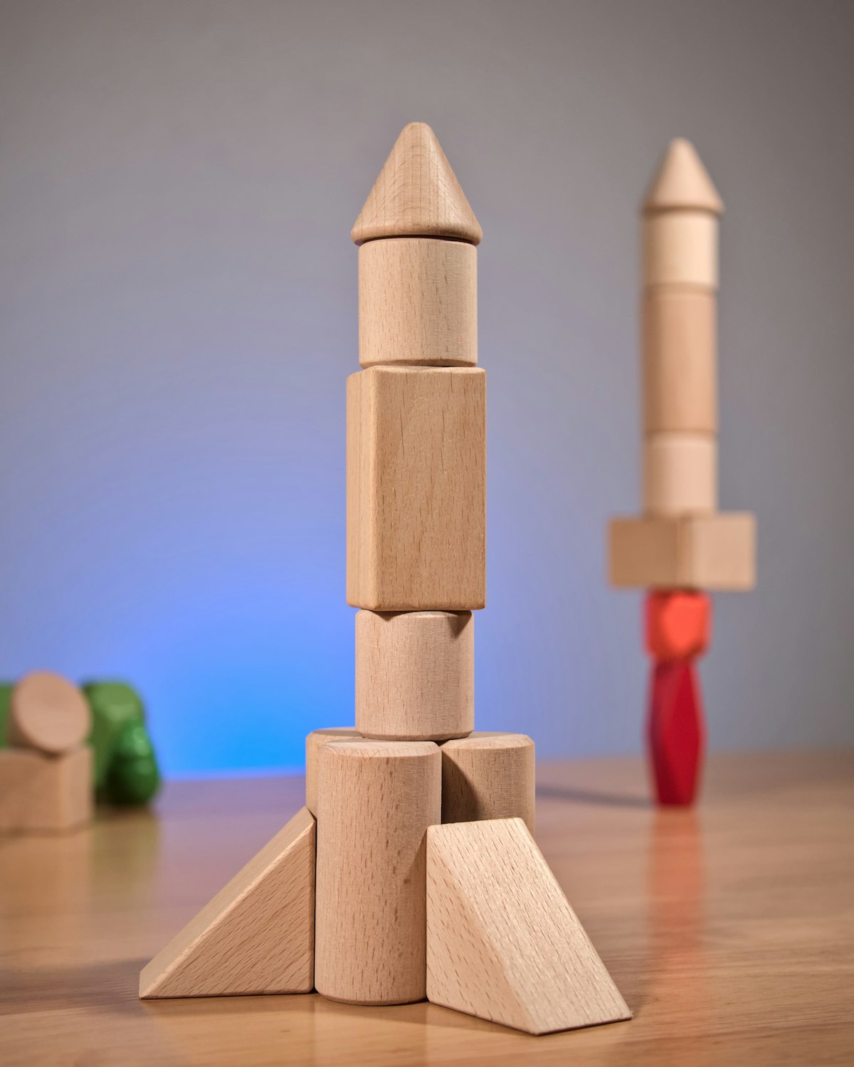 A rocket built from natural beech Whimble blocks — cones, cylinders and wedges stacked on a wooden table.