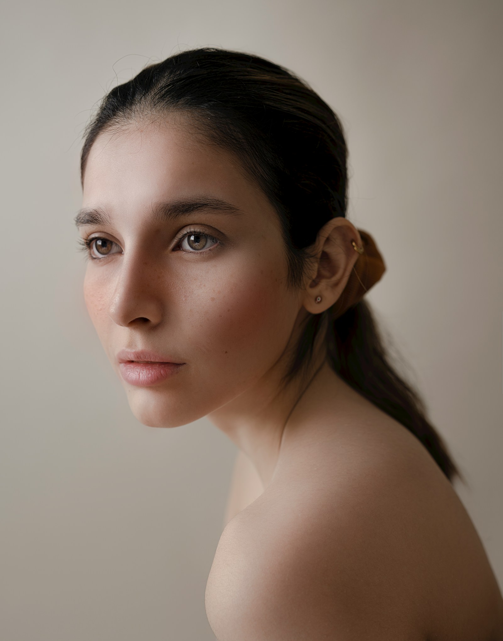 Case three, before state: side-lit studio portrait on a warm neutral ground, shown in a cooler grade.