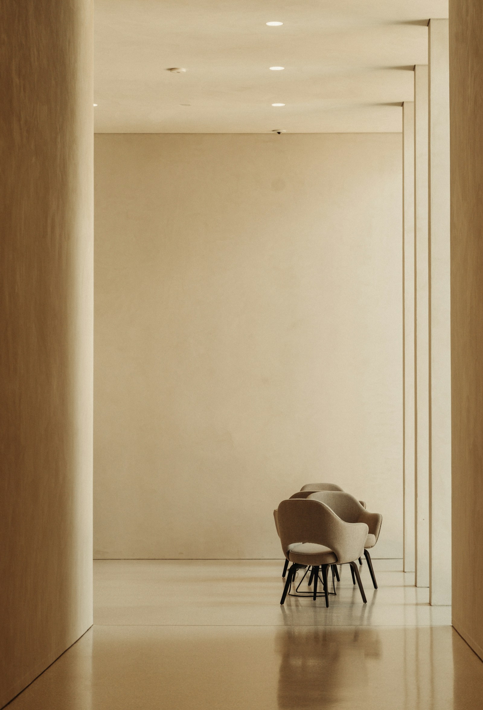 A quiet limestone corridor inside the clinic with waiting chairs at the far end.