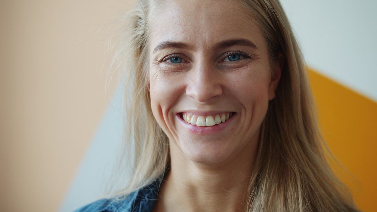 Marta Kowal, independent nurse prescriber — close studio portrait of a smiling fair-haired woman.