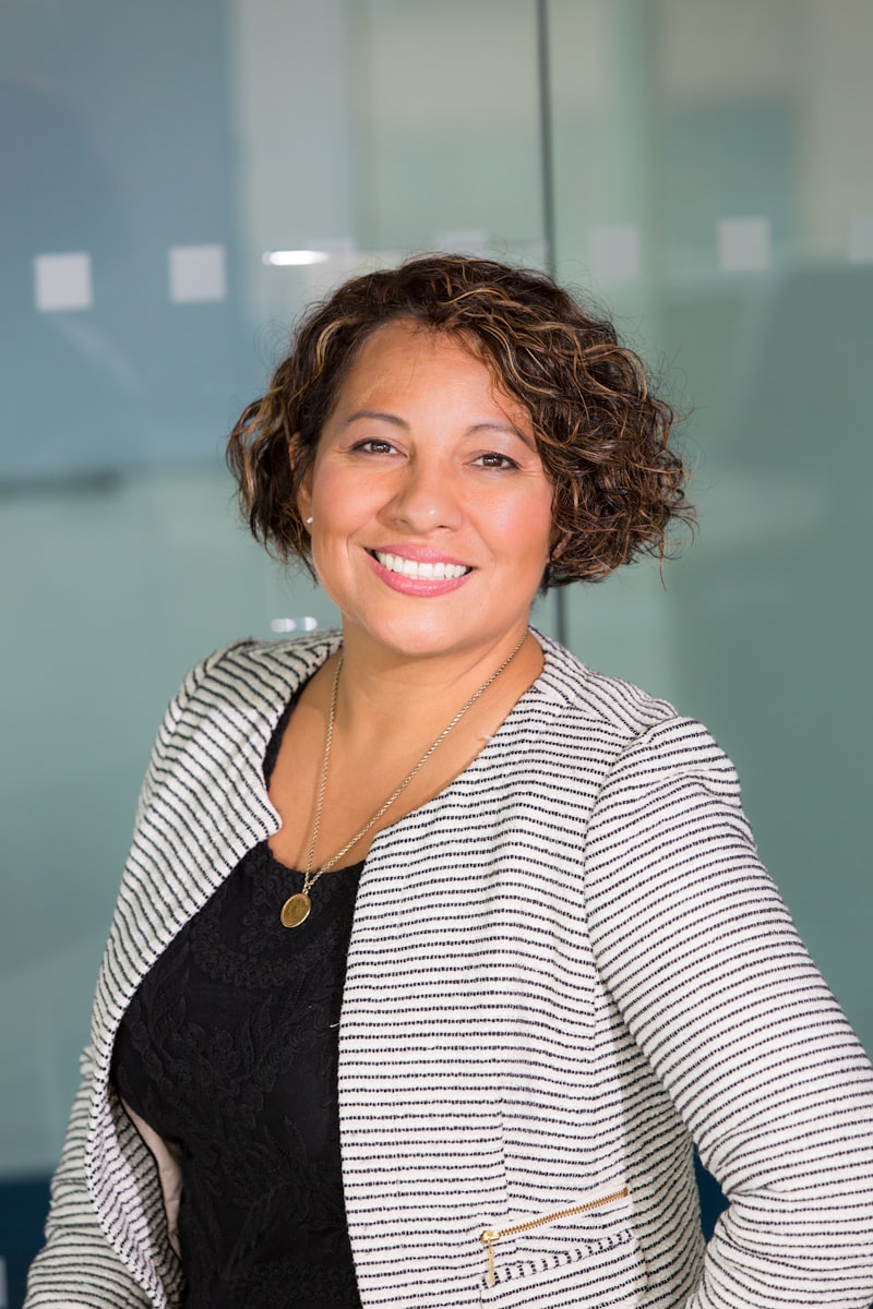 Portrait of Dr. Amara Ellis, a warm, smiling therapist in a striped jacket