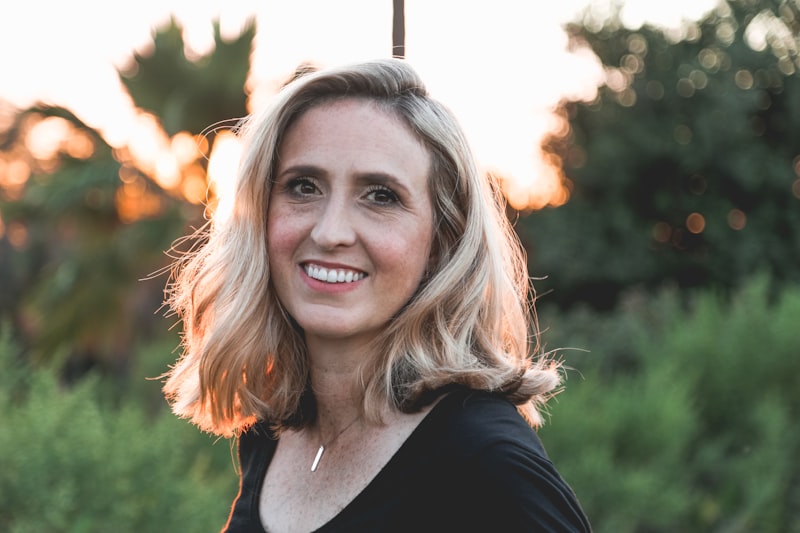 Portrait of Rosa Lindqvist, a therapist smiling warmly outdoors in golden evening light