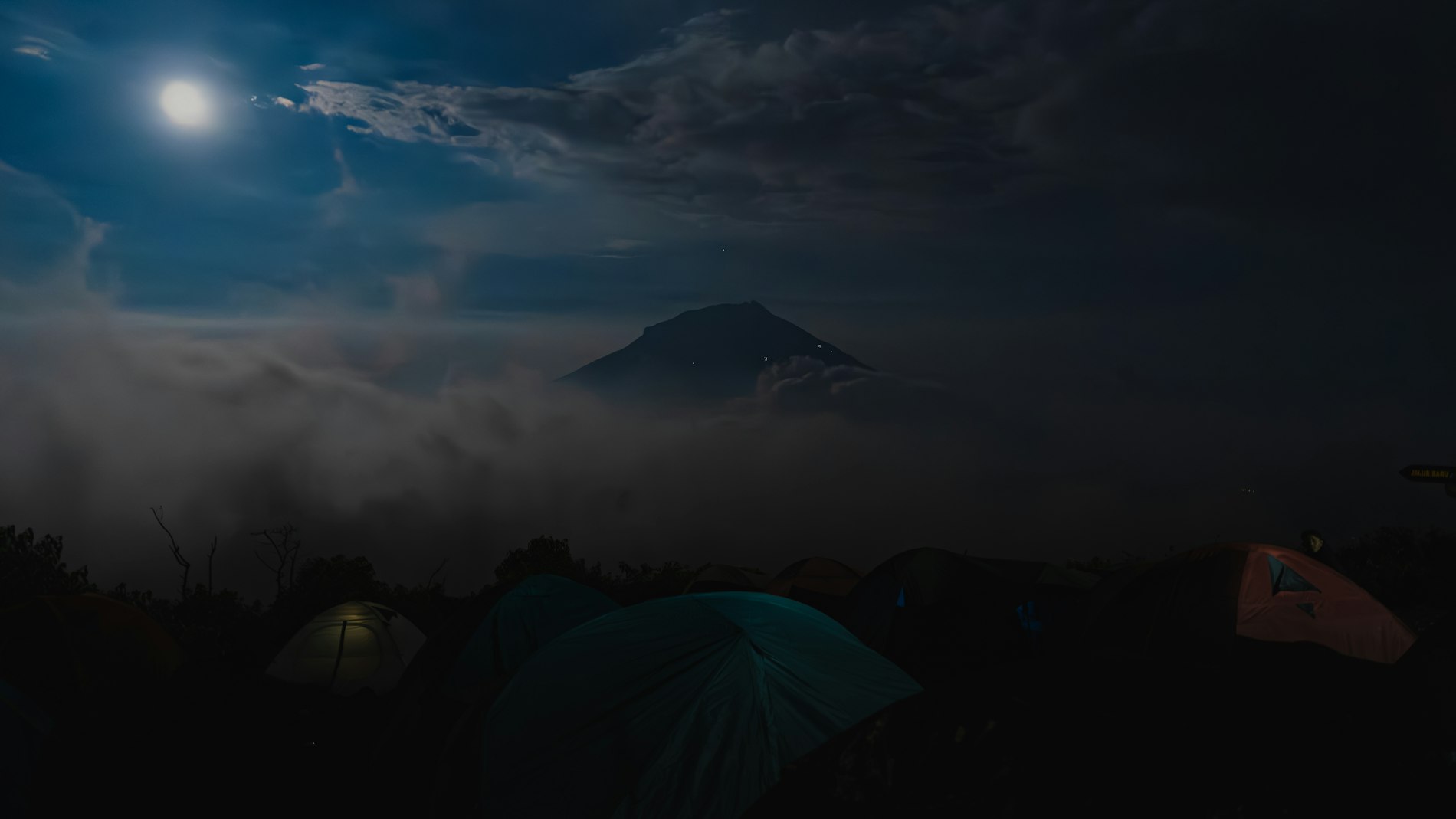 Tents pitched on a high ridge above a sea of cloud, lit by a full moon