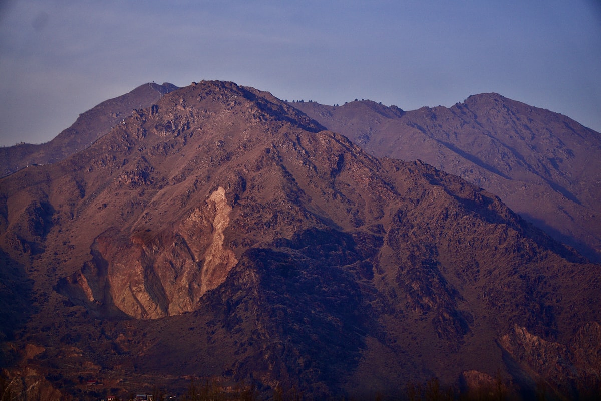 Ridge of a bare mountain at dusk showing deep erosion gullies like contour lines