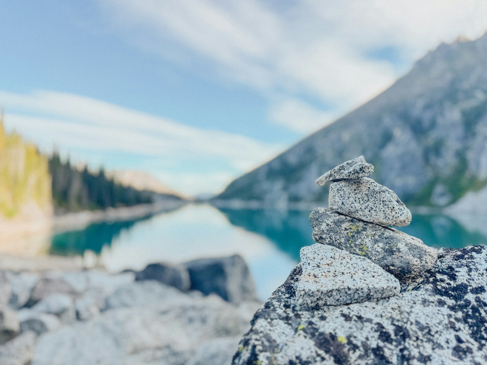 Granite cairn stacked on a boulder beside a still alpine lake