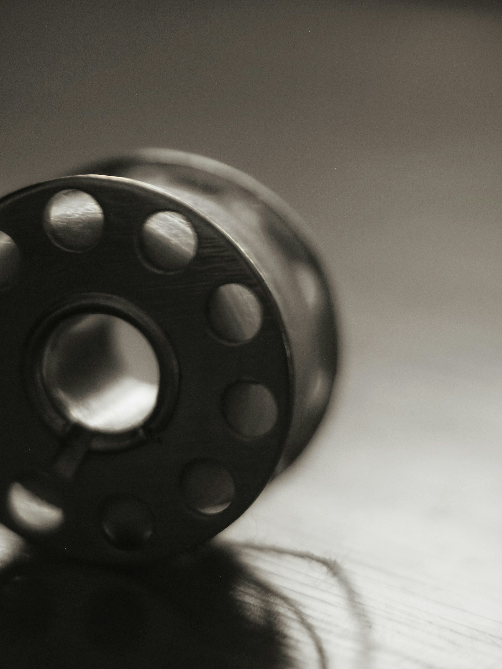 Close-up of a steel sewing-machine bobbin resting on a workbench