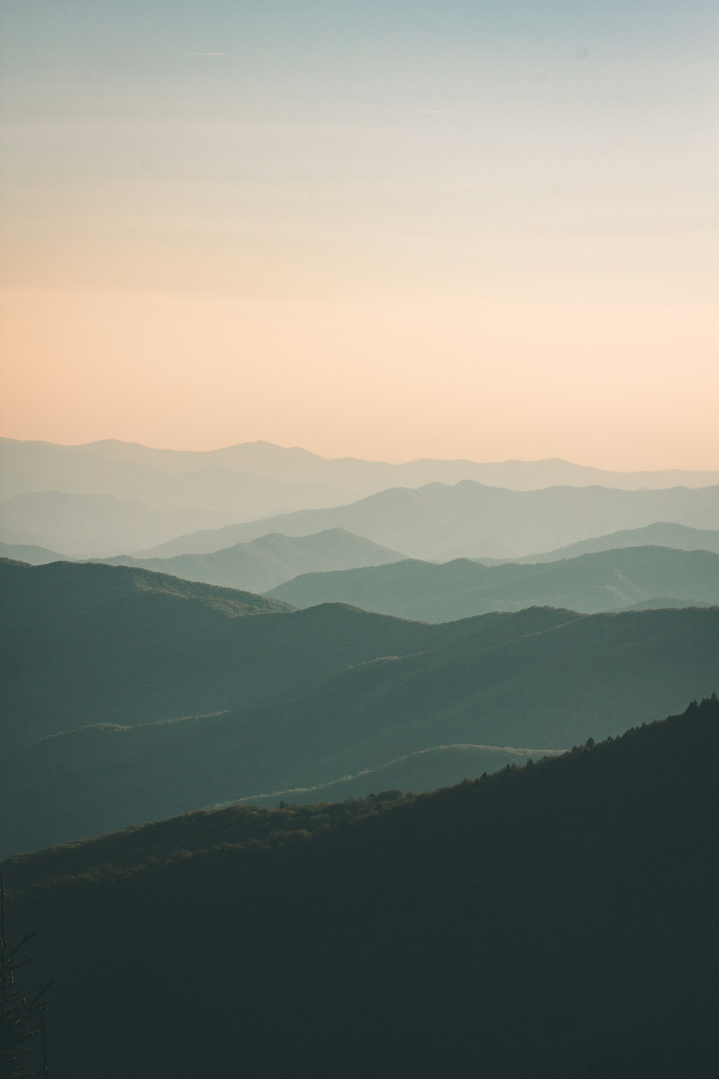 Pale fog pooling between dark mountain ridge lines in layered half light