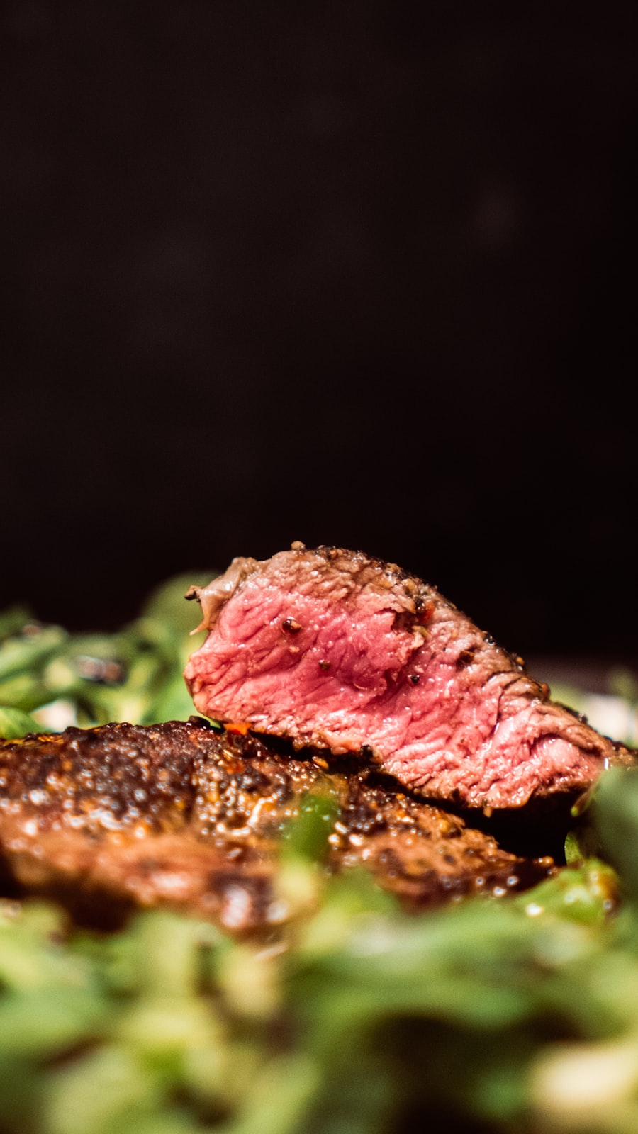 Slices of rosy aged duck breast plated against a dark background