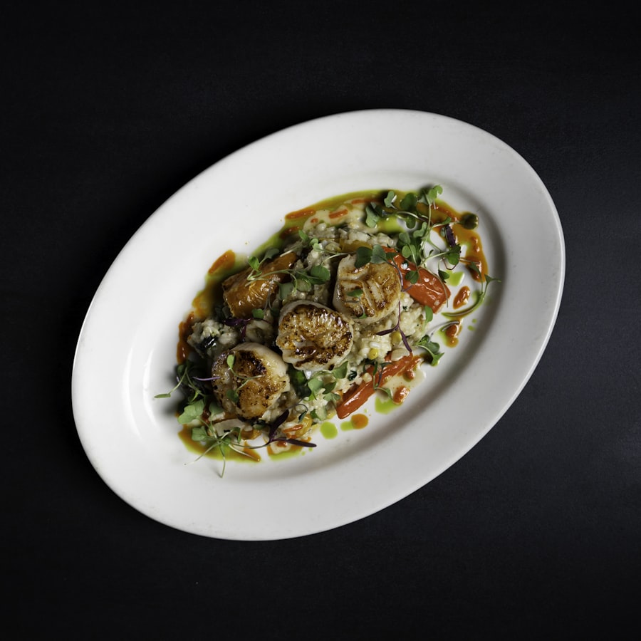 Seared scallops plated on white ceramic against a dark table