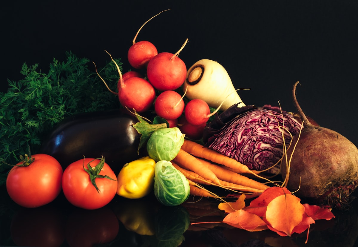 Beets, radishes, carrots, cabbage and aubergine arranged against a dark background