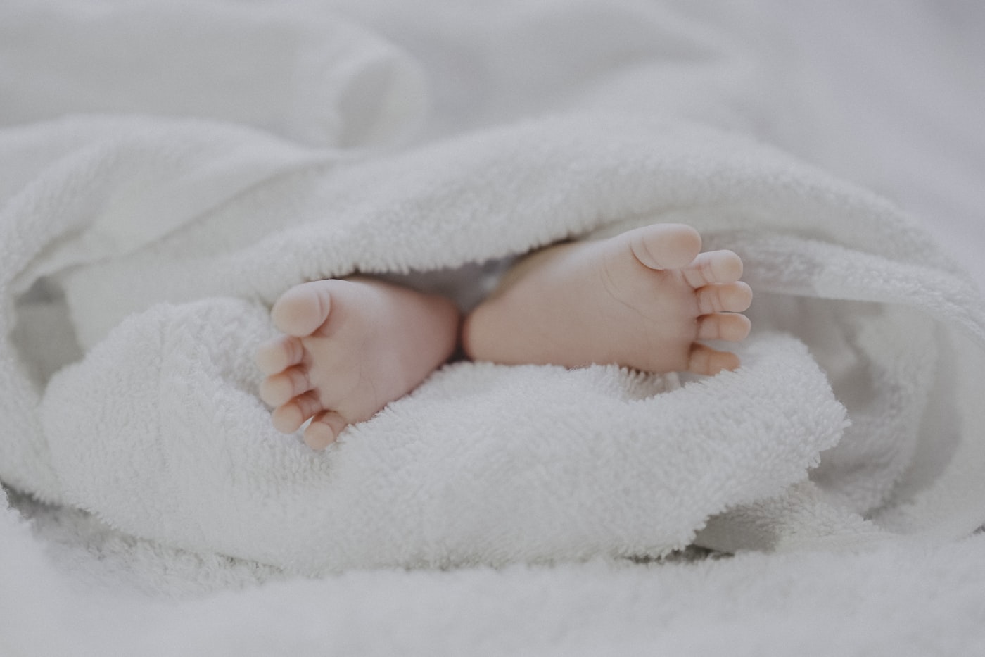 Bàn chân bé sơ sinh nằm trong khăn tắm bông trắng