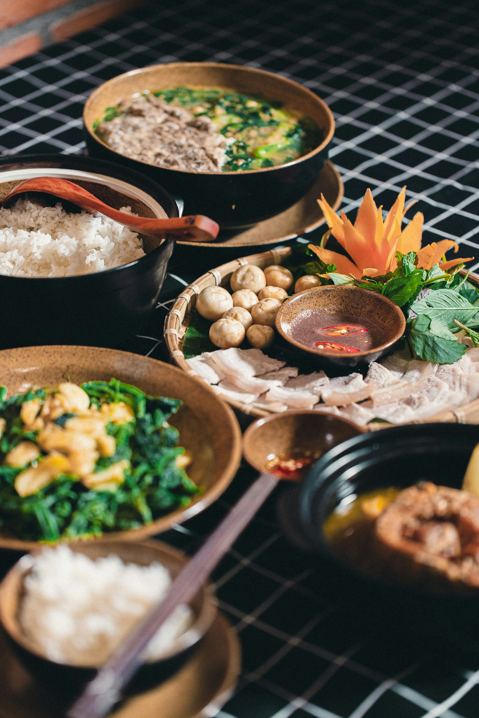 Mâm cơm gia đình gồm canh rau, thịt luộc, rau xào và cơm trắng bày trên bàn.