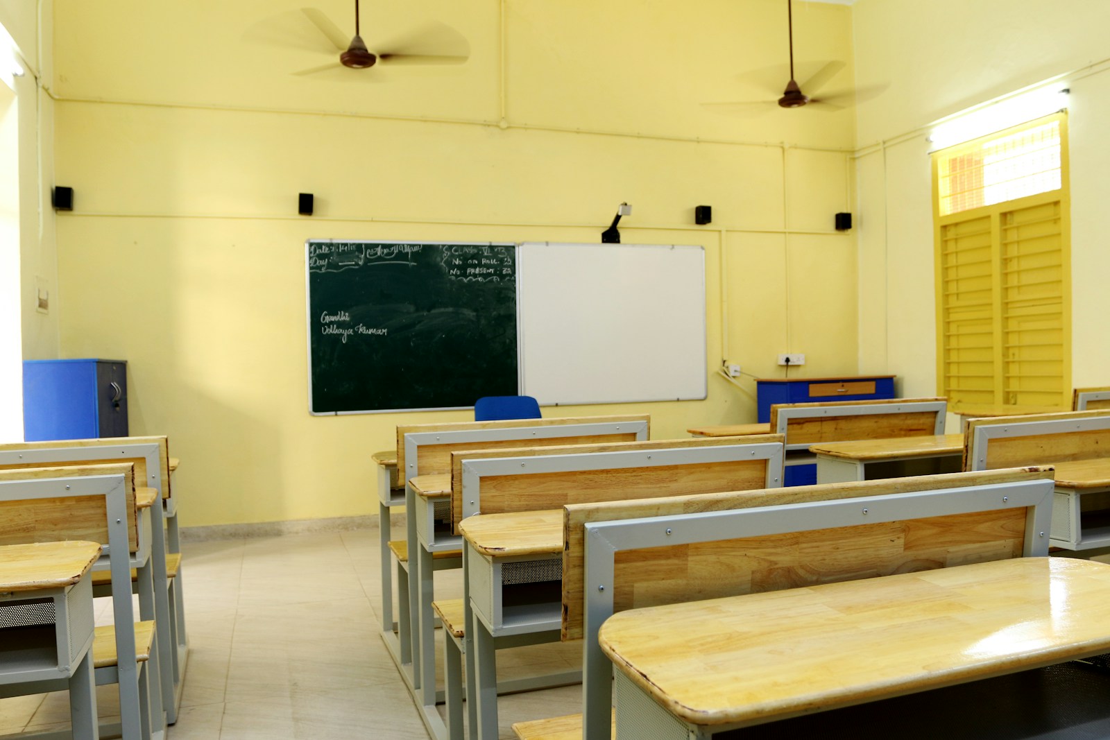 Phòng học trống với bàn ghế gỗ xếp thẳng hàng hướng về bảng trắng