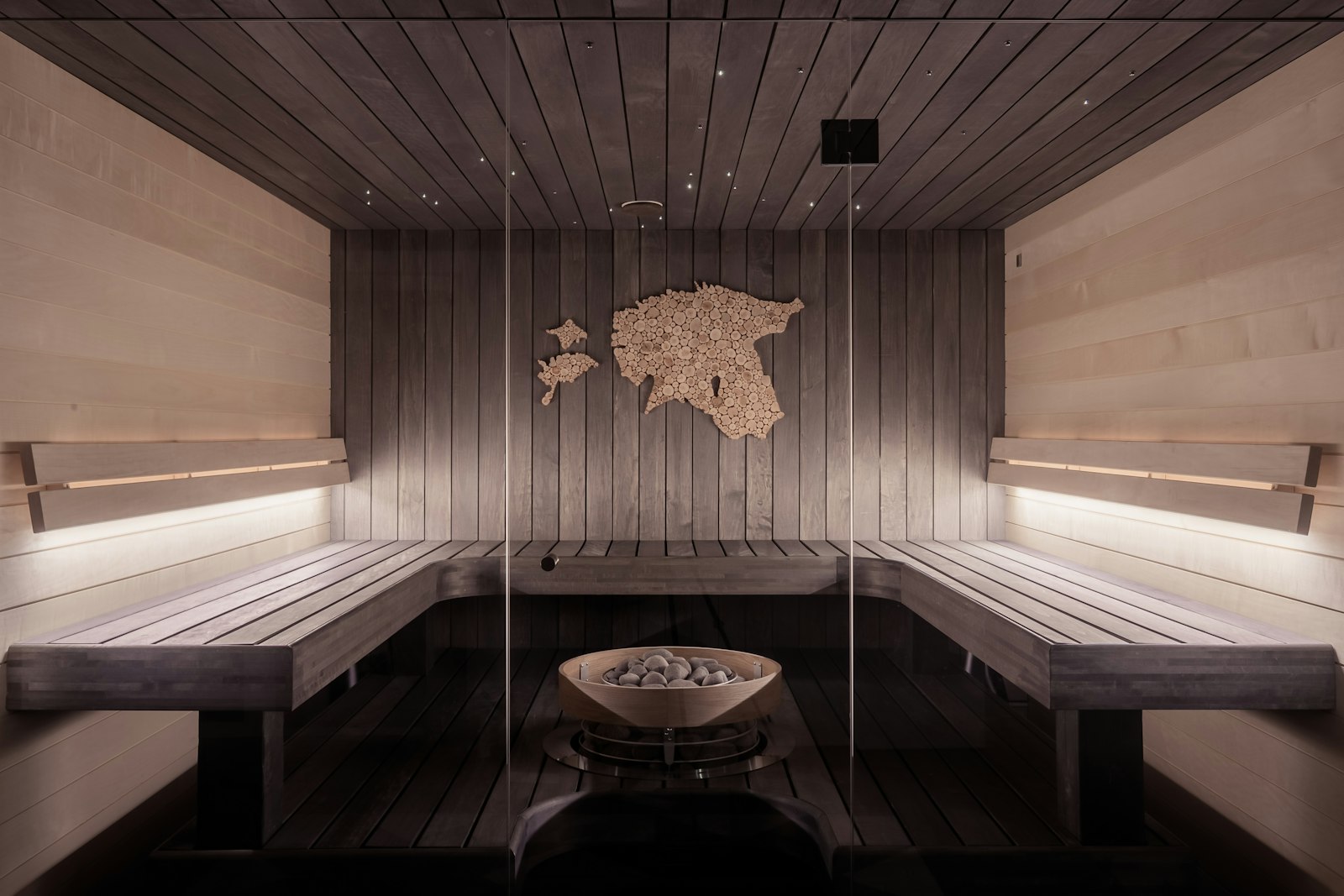 The cedar sauna at Stillwater, lined with pale wood benches and a stone heater