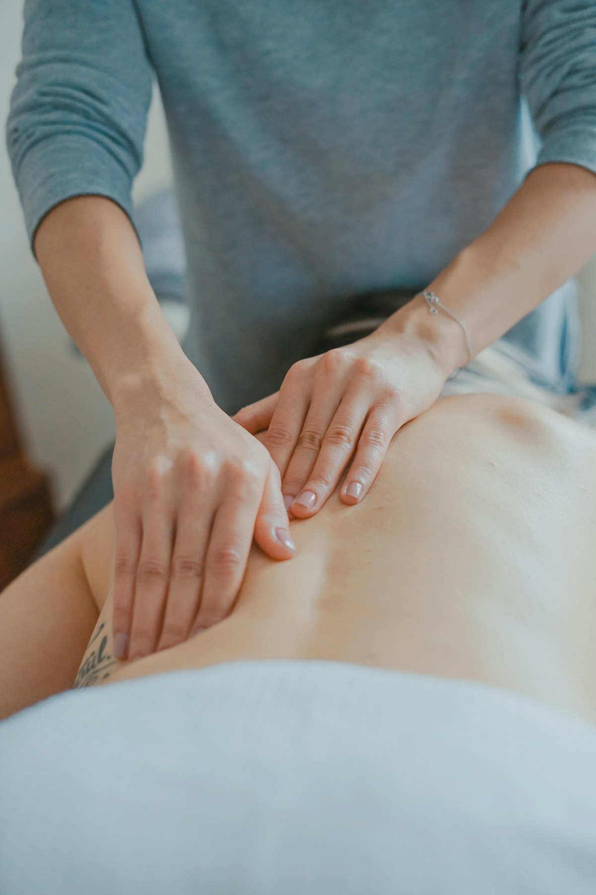 Massage therapist working along a client's back with both hands in a quiet treatment room