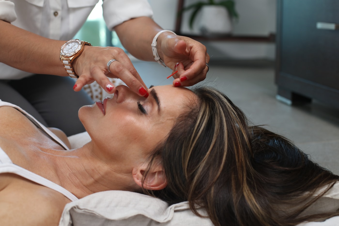 A guest lying with eyes closed while a therapist works along the brow during a botanical facial
